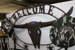 lot 65 image: Metal Longhorn Welcome sign with two camo hats