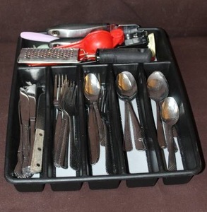 lot 114 image: black plastic silverware and utensil drawer organizer filled with various pieces of flatware and kitchen tools