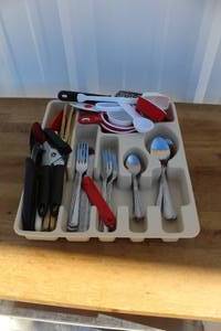 lot 113 image: White plastic silverware and utensil drawer organizer filled with various pieces of flatware and kitchen tools