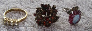 lot 11 image: 3 RINGS - ONE RED STONE ADJUSTABLE, ONE GOLD BAND 4 CLEAR STONES, ONE SIE 5 PRINCESS