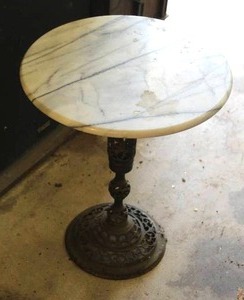 lot 4 image: vintage collectible is a Hollywood Regency style side table featuring a round white marble top and wrought iron pedestal base. an ornate, reticulated