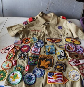 lot 583 image: vintage Boy Scouts of America uniform shirt features numerous insignias, badges, and commemorative patches from various events and councils.