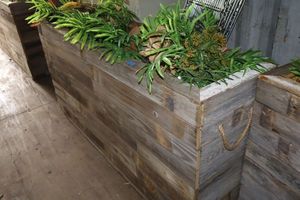 lot 135 image: Decorative wooden plant box - 61.5X17x31.5, does have small wheels on bottom.