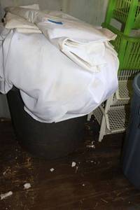 lot 55 image: Trash bin full of white tablecloths and linens (need cleaning)