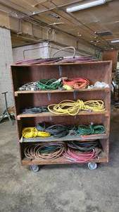 lot 314 image: Wooden Double-Sided Rolling Shelf Full of Extension Cords & Air Hoses.  Buyer must take cart & all.