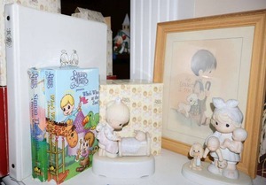 lot 33 image: Precious Moments figurines (one is musical, one has been reglued), wall art, and VHS movies