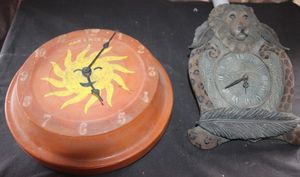 lot 55 image: Pool master 12-inch Terracotta indooroutdoor wall Clock Featuring a Painted Sun Design Alongside a Vintage style Clock with a Sculpted Lion Head and Feather Motif