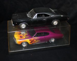 lot 121 image: Two 118 scale Diecast Muscle Cars, Featuring a Black 1968 Dodge Charger and a Purple 1970 Dodge Charger with Custom Flame Paint Job. 1 Display Case Included