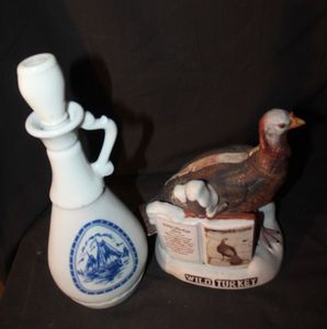 lot 219 image: Vintage Decanters 1963 Jim Bean Beans Choice Whiskey decanter featuring a blue and white delft sailboat design. a Vintage1980 Austin Nichols Wild Turkey porcelain decanter from the Lore Series #2