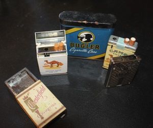 lot 316 image: Vintage tobacciana collectibles featuring branding from popular cigarette companies, Buglar Case (tin) Camel Lighters and Chesterfield pack