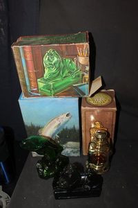 lot 361 image: Three Vintage Avon Decanters with Original boxes. Classic Lion Dark Green or Black Glass. Auto Lantern in Amber Glass, and Rainbow Trout typically made of green glass