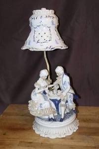 lot 58 image: vintage porcelain boudoir lamp featuring a blue and white design of a Victorian couple sitting at a table