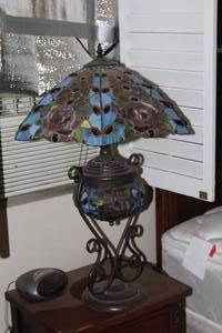 lot 519 image: Tiffany-style stained glass table lamp featuring a blue, purple, and green floral shade on a dark bronze base