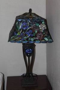 lot 520 image: Tiffany-style stained glass table lamp featuring a blue floral and iris design with a dark metal base