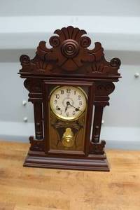 lot 650 image: dark brown carved wood gingerbread mantle clock featuring an ornate pediment and a pendulum