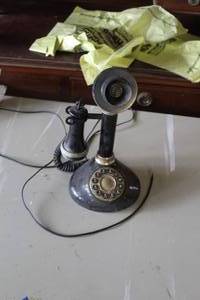 lot 714 image: vintage black candlestick style telephone with a rotary dial and handset.