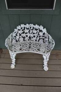 Victorian-style white cast iron garden bench featuring a grape vine and leaf pattern