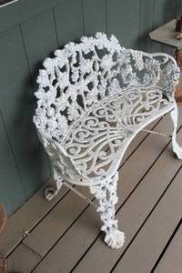 Victorian-style white cast iron garden bench featuring a grape vine and leaf pattern