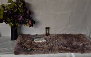 lot 188 image: Home Decorations, Purple Glass vase with faux flowers, vase is full of sequences, lavender shag rug, Pink and black Moon plaque, and Explore world sun catcher, and sand timer with compass