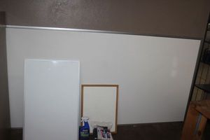 lot 233 image: Very large White board, and two smaller white boards, Gallon size bag of white board markers, erasers and a bottle of white board cleaner