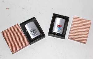 lot 128 image: Zippo windproof lighter featuring an engraved United States Navy seal and its original box and  Zippo  lighter featuring a commemorative design for CO K 14th REGIMENT with a Southern-themed emblem in its original box