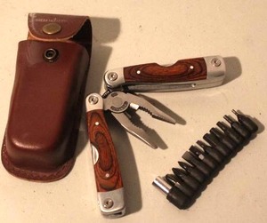 lot 132 image: stainless steel multi-tool set featuring wood handle scales and a leather sheath
