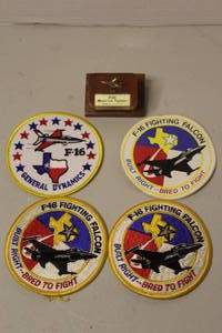 lot 203 image: gold-tone metal model of an F-16 Fighting Falcon in resin on a wooden base and patches for the General Dynamics F-16 Fighting Falcon fighter aircraft