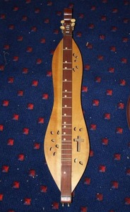 lot 351 image: wooden mountain dulcimer featuring a traditional hourglass body shape and decorative soundholes