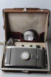 lot 375 image: vintage Polaroid Land Camera Model 800 featuring a brown leather case and a flash unit