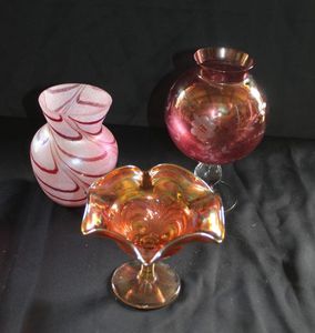 lot 108 image: Teleflora iridescent pink art glass vase, Fenton Marigold Carnival glass ruffled compote candy dish, and a vintage cranberry glass globe vase.