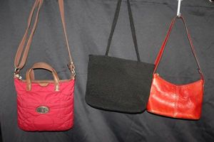 lot 251 image: Three Purses Left- Fossil Key-Per Quilted Crossbody in Cranberry red nylon material with brown leather top handles and adjustable fabric strap, Center- classic canvas tote bag by The sak, and Vintage Red Leather Fossil shoulder bag
