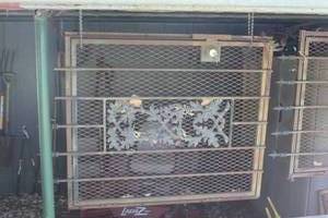 lot 394 image: a decorative security screen door featuring a central ornate floral panel and a diamond-mesh pattern