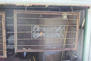 lot 396 image: a decorative security screen door featuring a central ornate floral panel and a diamond-mesh pattern