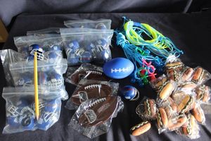 lot 74 image: Bulk lot of Football helmets and footballs, hotdog key chains and plastic pacifiers, football shaped bottle openers