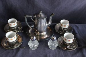 lot 111 image: Vintage Coffee set features 5 porcelain cups with saucers in metal-handled holders, a teapot a sugar bowl and a creamer.