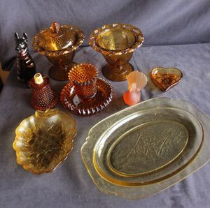 lot 153 image: Vintage Amber-Colored Glass Pieces, Indiana Glass Grapevine pedestal candy dish, Tiara Moon and Stars Candy Dish, Carnival Glass ruffled rim compote, Avon Dog Decanter, Thumbprint pattern dish and more