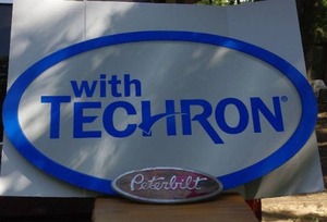 lot 21 image: Large oval metal Techron sign and small metal Peterbilt sign