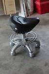 rolling pneumatic shop stool featuring a motorcycle-style saddle seat