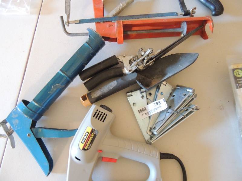 lot 793 image: 8 brackets, 2 poly guns, electric stapler, and a hand saw