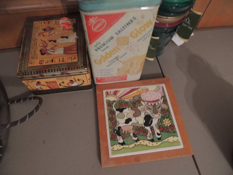 lot 827 image: Vintage cracker tin, Holiday time bucket, cow trivet and Egyptian tin can