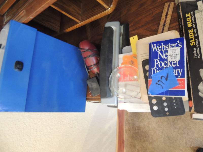 lot 372 image: Desk materials- hole punch, Webster dictionary, slide rule etc.