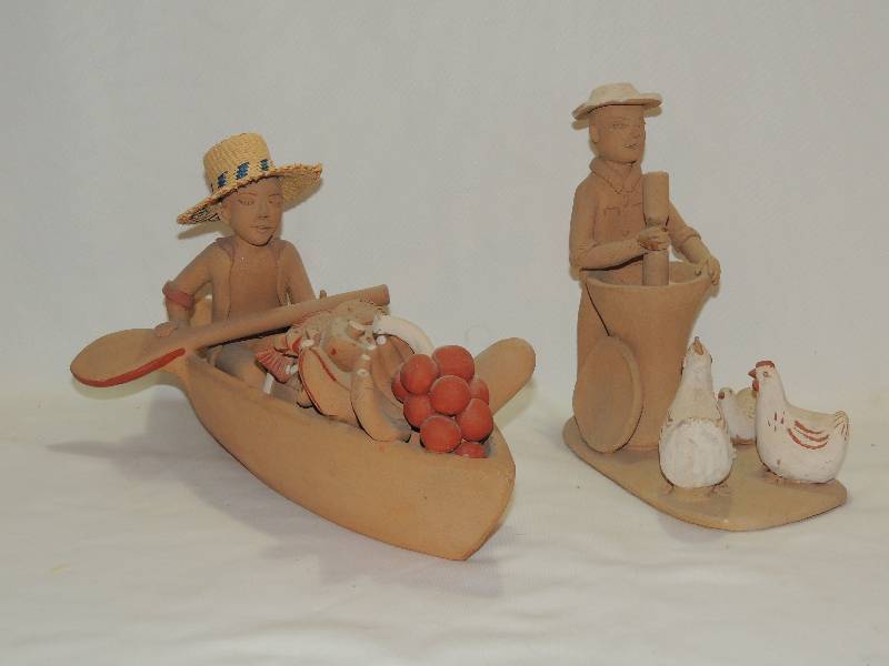 lot 187 image: Pottery Sculptures- Man with chicken 8 grinding corn   man in canoe carrying fruit 9 length