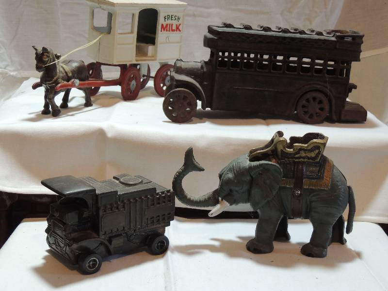 lot 290 image: Cast iron Toys.-  Fresh Milk Wagon with horse and driver, Bus, Elephant bank, and metal truck bank