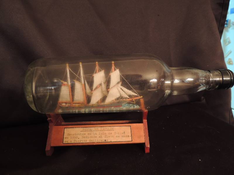 lot 19 image: Ship in a bottle on wood stand Ship 5 long bottle 11L Bergautin Maullin 1899