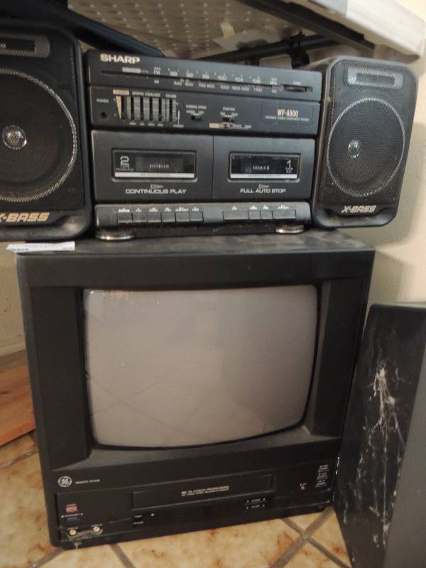 lot 25 image: 2 Televisions 1 GE with VHS and Montgomery Wards with push buttons. Sharp Radiocassette player and 1 Magnavox VHS All unknown working condition