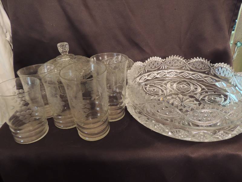 lot 53 image: Pressed glass- 10 fruit bowl, covered candy dish, Pedestal cake plate, divided serving plate, 9 bowls, sugar bowl, salt cellar, salt spoons, cut glass pitcher with matching glasses x 6 and 7 7 grape design juice glasses