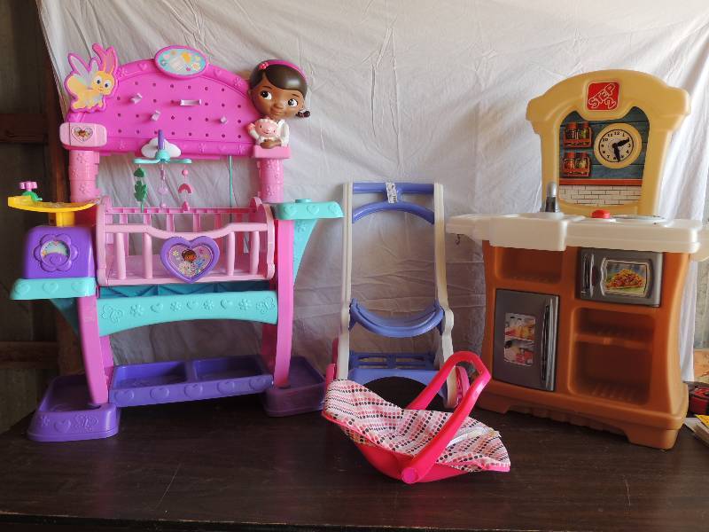 lot 707 image: Step 2 kids kitchen. Has refrigerator, microwave, storage , one burner stove and sink.  Mini shopping cart missing back, baby doll carrier, baby doll nurse changing and weigh station