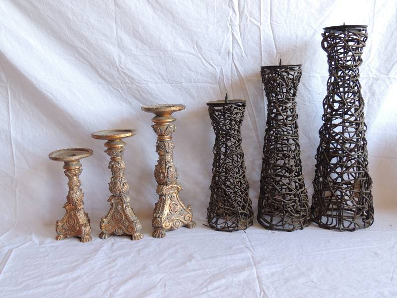 lot 732 image: 2 sets of candle stand. Black set is wrapped in wicker. Sizes are 18 15 12. Gold set has floral dcor. Sizes are 12 10 8