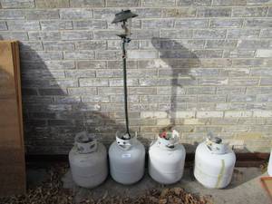 lot 47 image: 4 PROPANE TANKS A COUPLE HAVE SOME PROPANE AND SMALL COLEMAN LIGHT WITH BROKEN GLOBE
