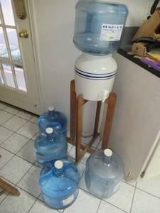 lot 83 image: WOOD AND CERAMIC WATER DISPENSER WITH 3 WATER JUGS AN D 1 EMPTY JUG